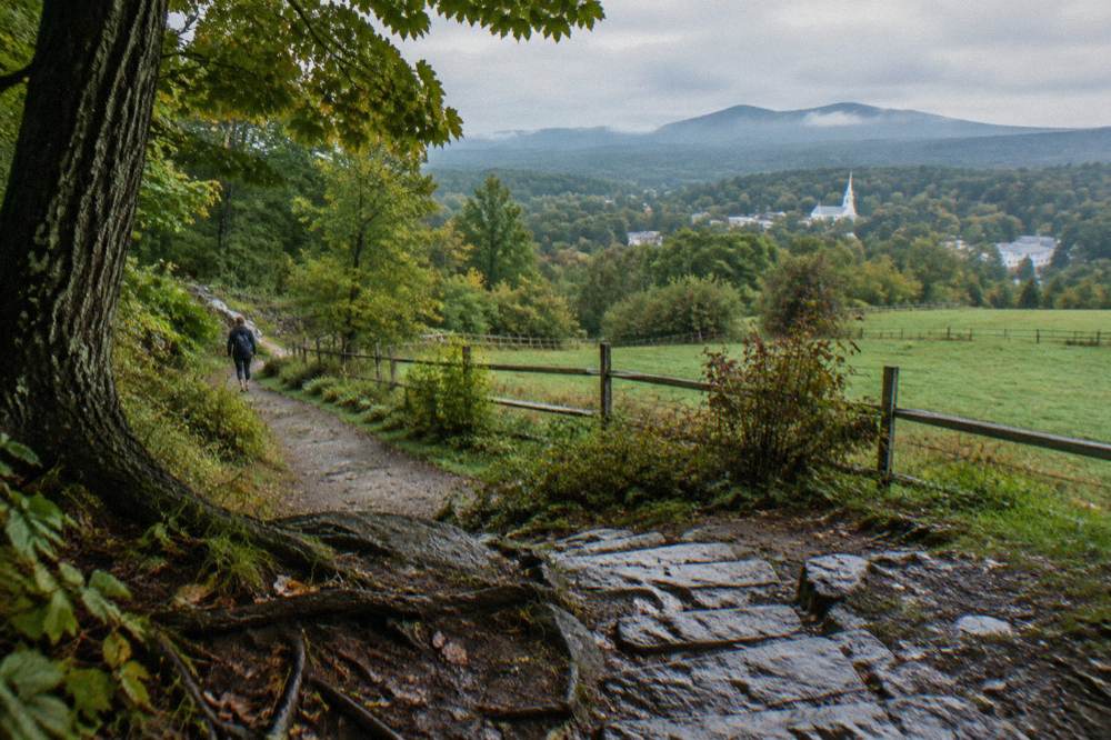 A quiet paved bike path winding through green countryside with hills in the distance