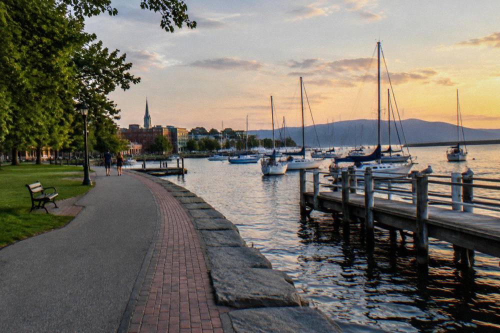 A lakeside bike path curving past a city waterfront with boats moored in a harbor