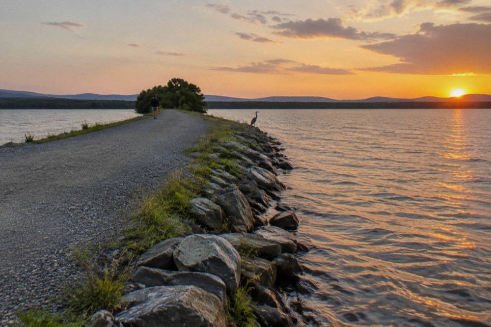 A gravel bike path crossing a narrow causeway with open lake water on both sides