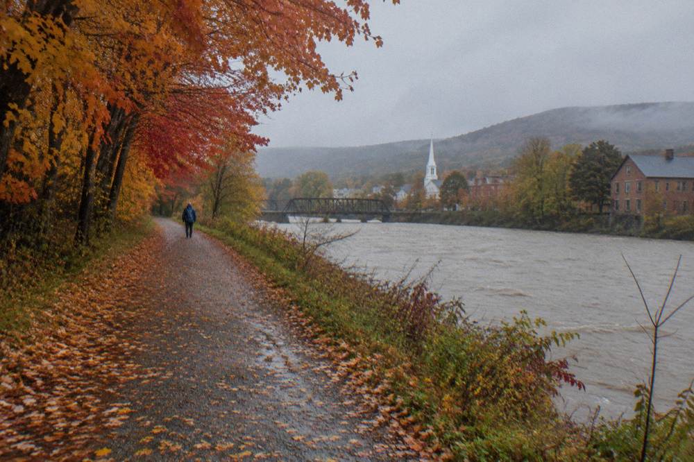 A rail trail winding beside a river through orange and red autumn trees