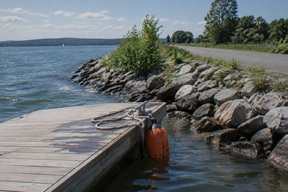 Bicycles parked at a wooden dock on a stone causeway waiting for a small ferry boat