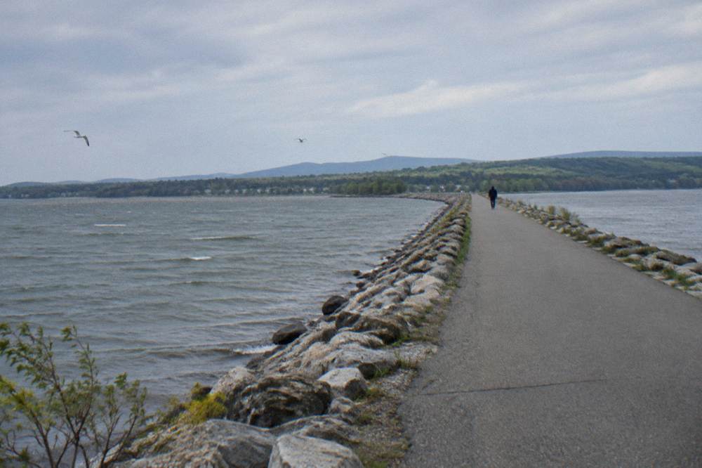 Straight stone causeway bike path crossing open lake water under a wide sky