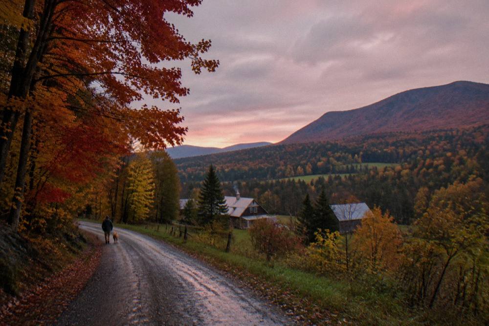Red and orange maple forest above a quiet valley road in northern Vermont