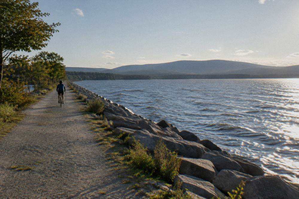 Cyclist riding a pedal-assist bike along a shoreline path