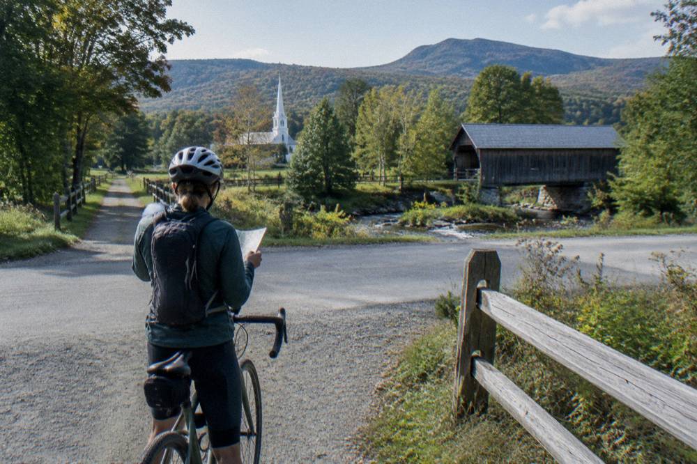 A cyclist stopping at a country crossroads to check a route sheet
