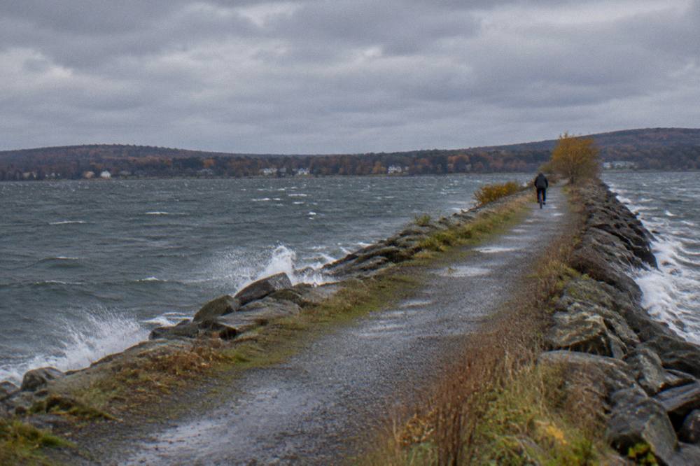 Lone cyclist on a lakeside causeway trail with open water on both sides