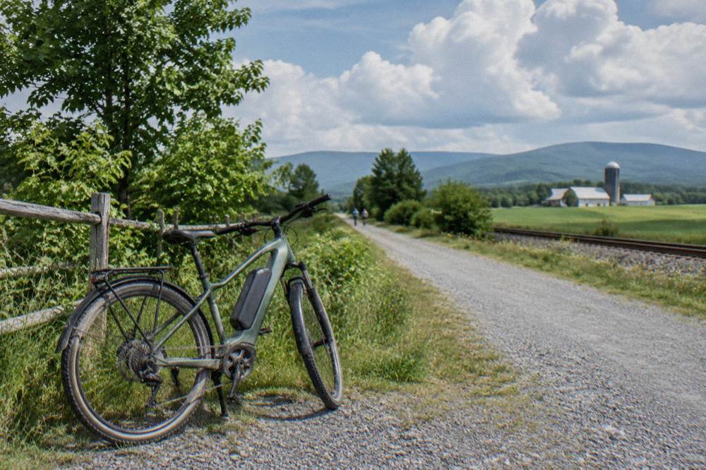 A pedal-assist e-bike parked at a trailhead sign beside a forest path