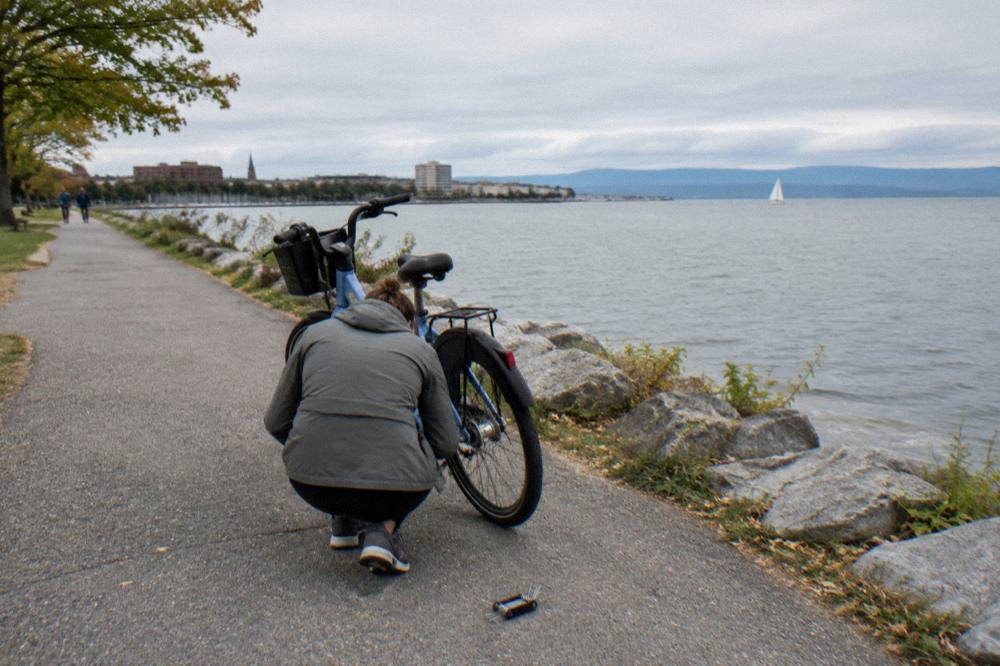 A rider crouched checking the tire of a bicycle outside a rental shop