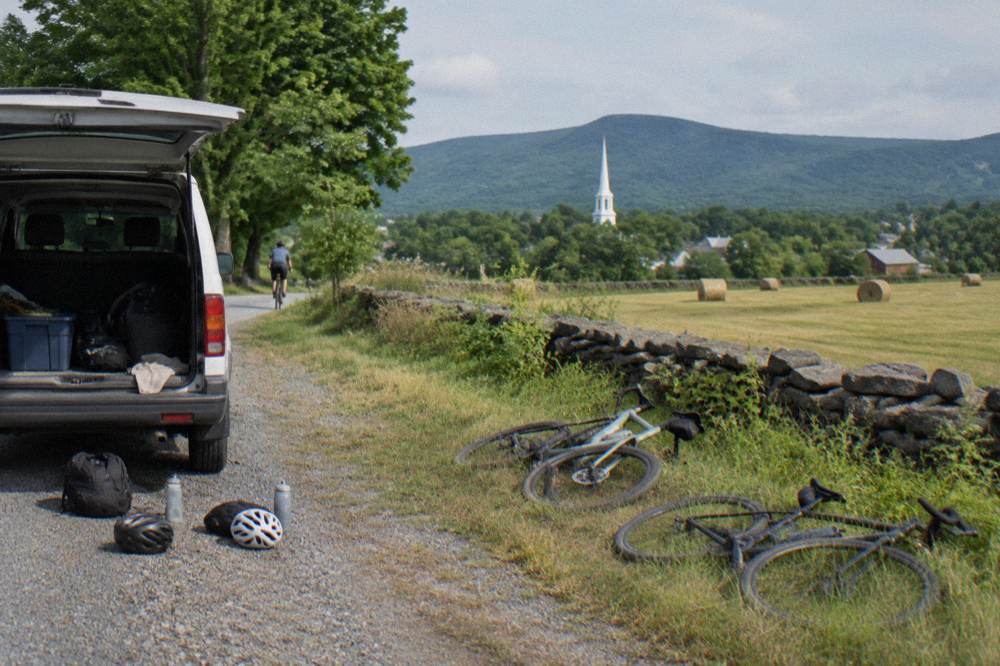 A support van parked beside a country road with bicycles unloaded