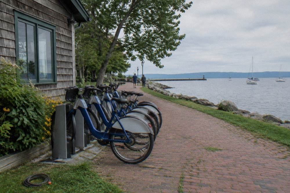 A row of rental bikes parked outside a small wooden shop in a green village
