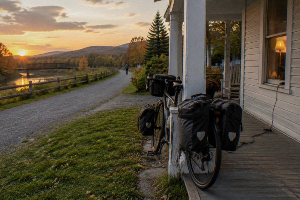 A bike loaded with panniers parked outside a white clapboard inn in a small town