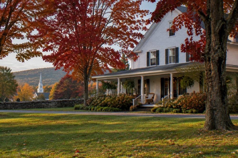 A country inn with a porch set among maple trees in full autumn color