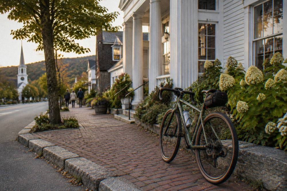 A lightly packed bicycle with a small seat bag and handlebar bag parked outside a Vermont country store
